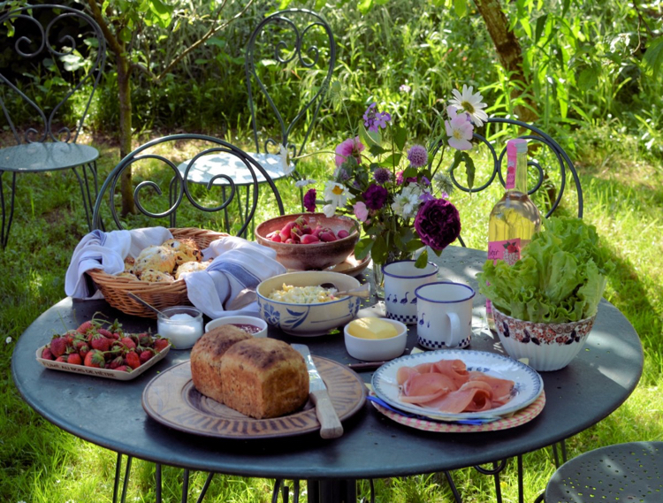 aire de pique-nique –jardin-table-ronde-chaises-fer-forgé-bouquet-fleurs-printanières-mets-savoureux