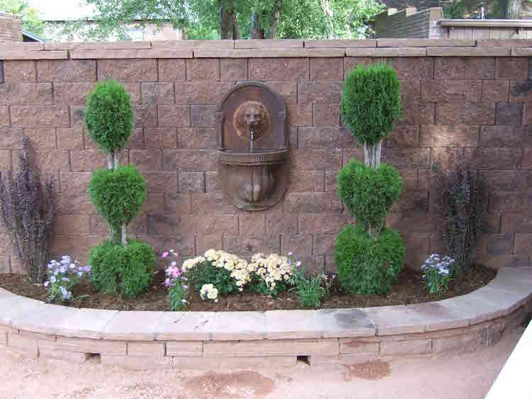 fontaine-murale-jardin-tête-lion-décorée-plantes-fleurs