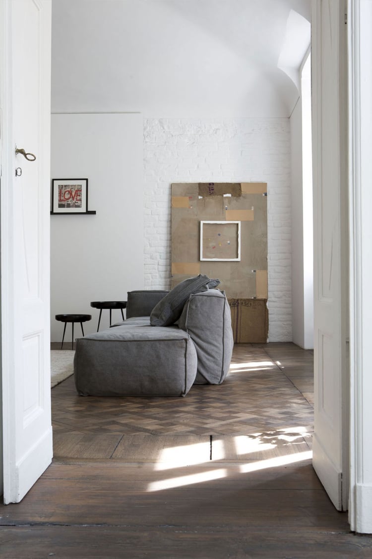 intérieur blanc et bois -salon-minimaliste-brique-parement-blanche-canapé-gris-rembourré-parquet-bois-massif