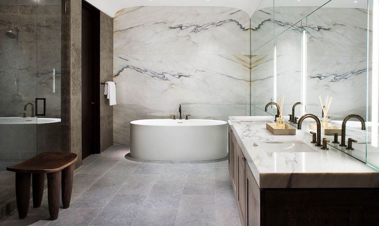 salle de bain en marbre au mur-derrière-baignoire-ovale-plan-lavabo-robinets-laiton