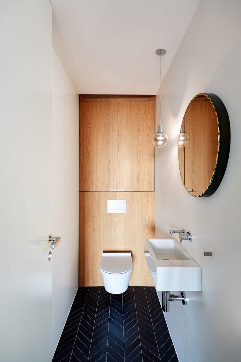 salle-toilettes-chic-carrelage-sol-noir-chevrons-cuvette-suspendue-miroir-rond
