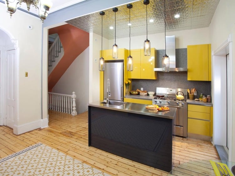 petite cuisine avec ilot central-plan-travail-métal-armoires-cuisine-jaunes-crédence-aspect-granit