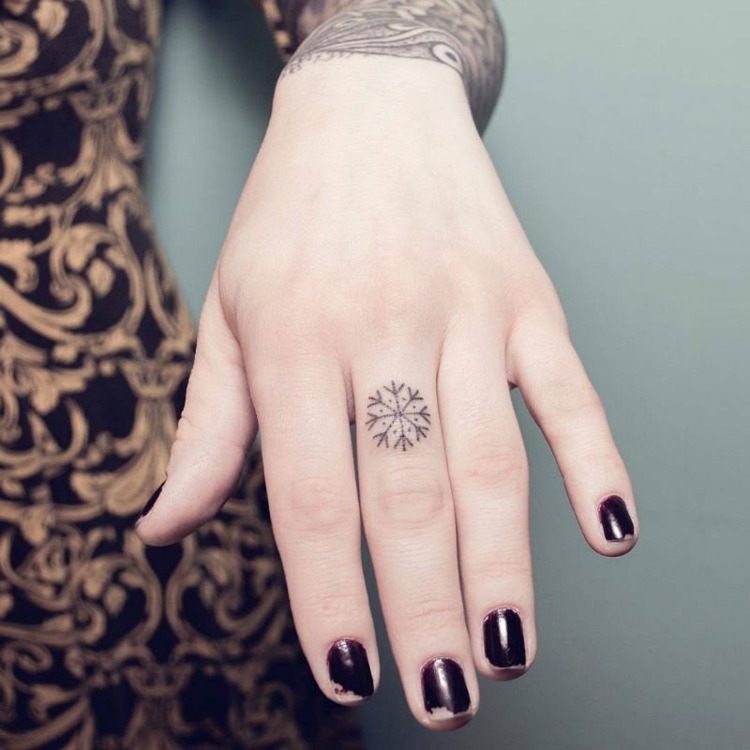 tatouage-doigt-femme-flocon-neige-majeur-style-écriture-runique