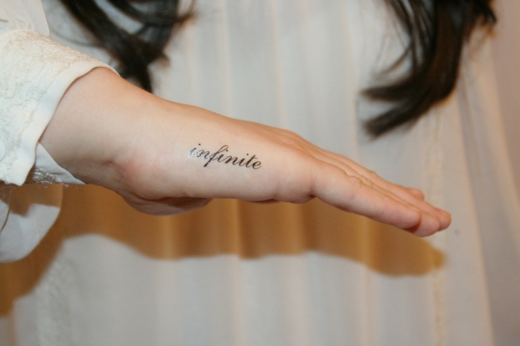 tatouage-femme-partie-extérieure-main-lettrage-infini-infinite