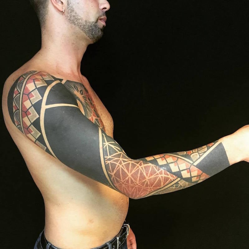 tatouage sur le bras homme blackwork noir rouge