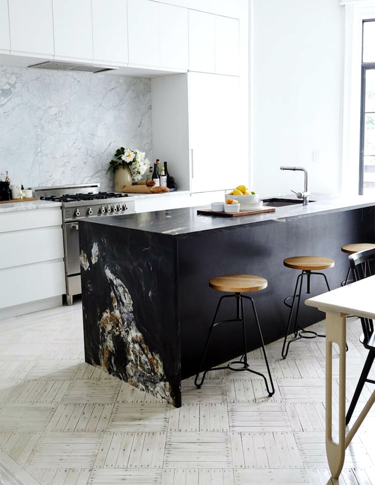 îlot central en marbre noir brut dans la cuisine blanche chic