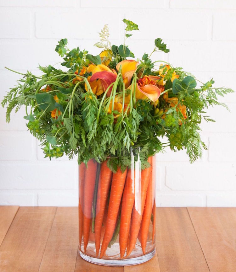 centre de table Paques en fleurs et carottes dans un vase en verre