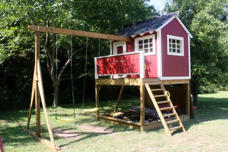 cabane en bois sur pilotis rouge et balançoires