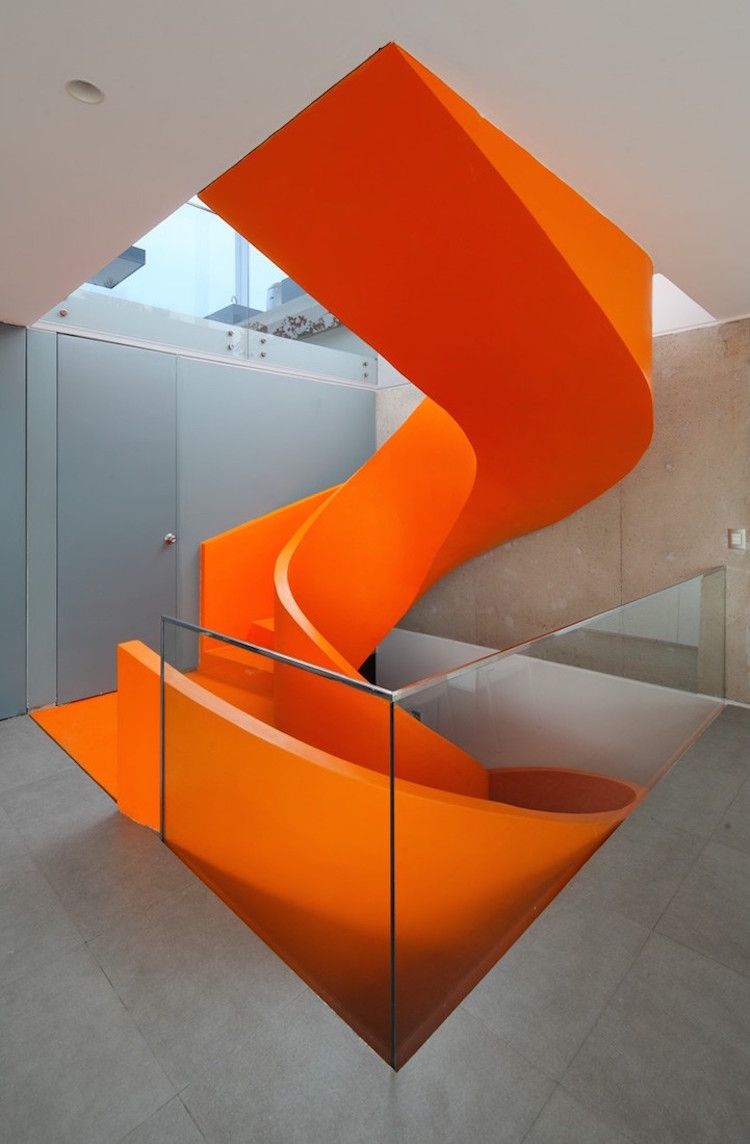 escalier spirale forme minimaliste orange sur un fond de béton gris