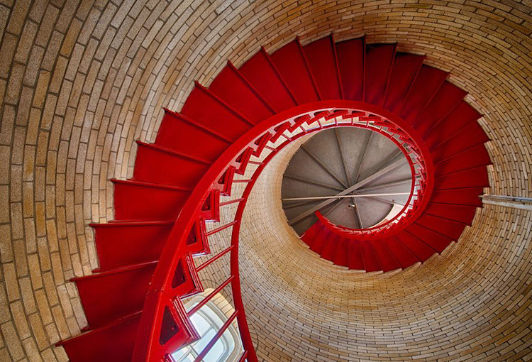 escalier spirale métallique rouge dans tour en brique