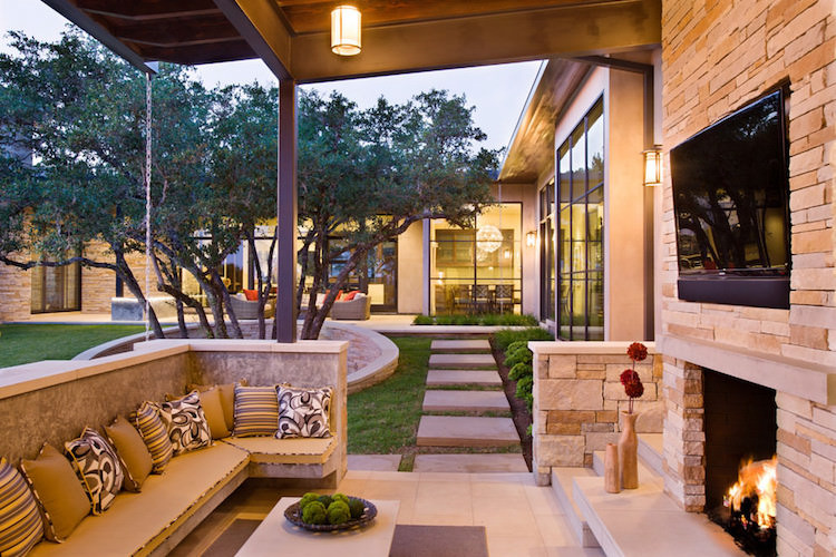 espace de vie exterieur moderne patio cheminee jardin pierre banquette coussins