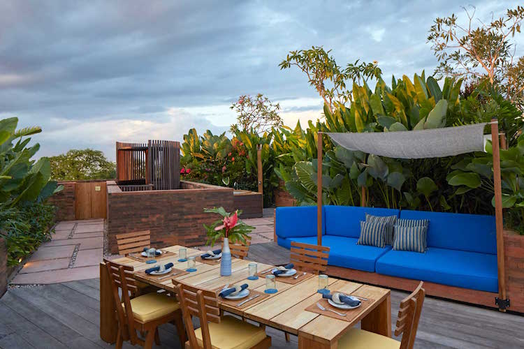 toit terrasse avec meubles en bois et verdure exotique