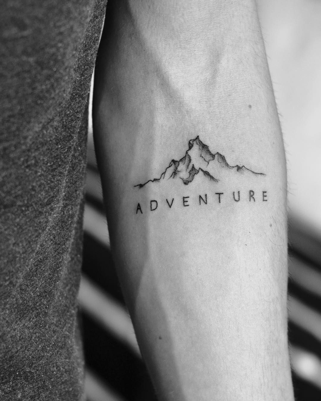 petit tatouage homme contours montagne mot aventure avant-bras