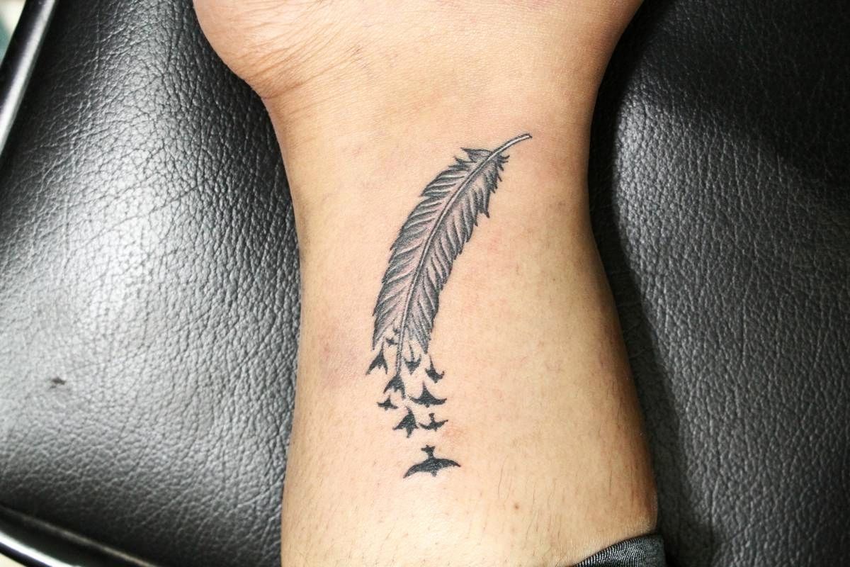 petit tatouage homme plume sur le poignet