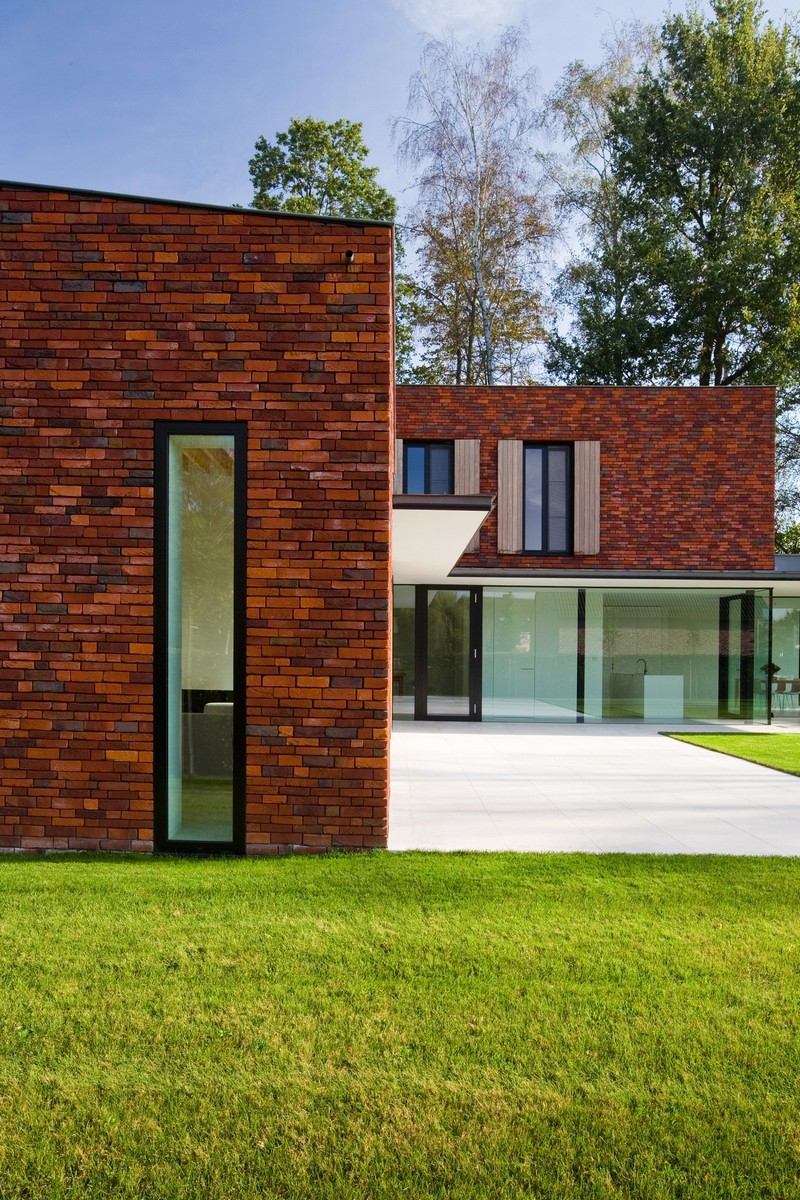 façade en brique baies vitrées coulissantes maison design paysage naturel gazon soigné