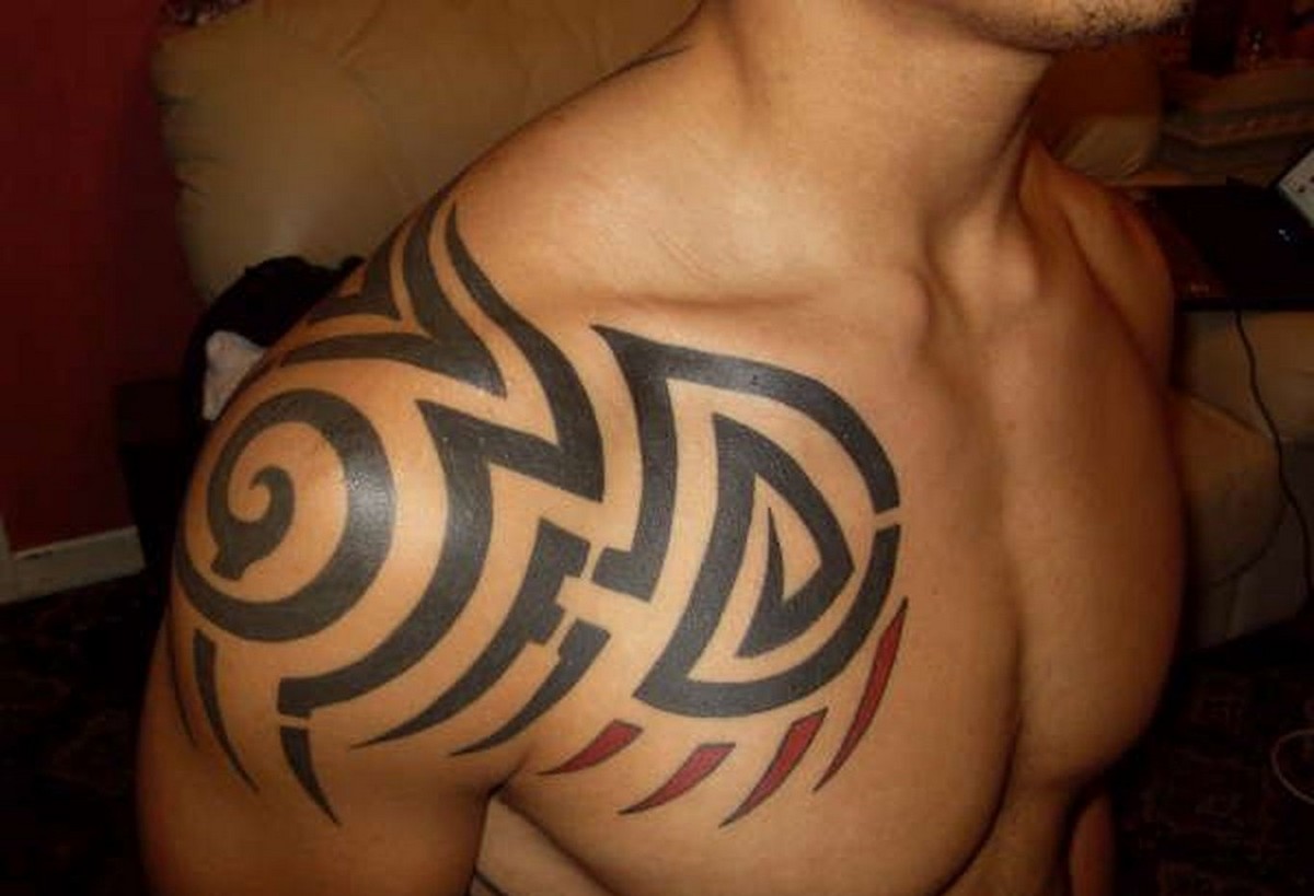 tatouage tribal sur le bras et la poitrine touches de rouge