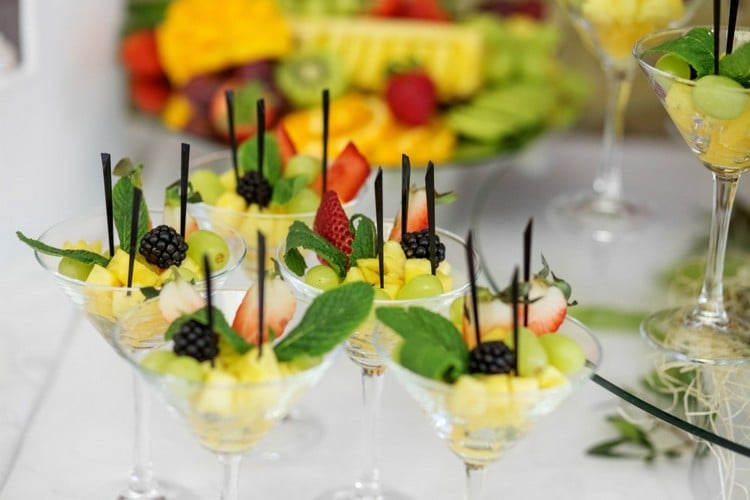 brochettes de fruits dans des verres à cocktail ananas fraises raisin mûres menthe