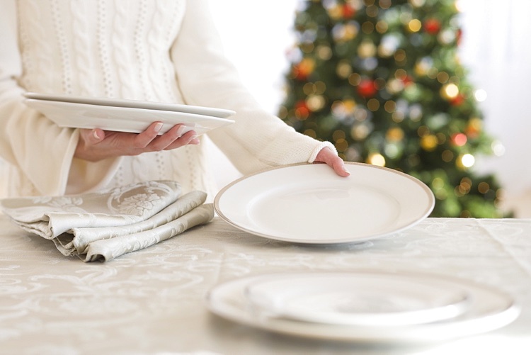 femme dresse table Noel assiettes blanches serviettes argentees