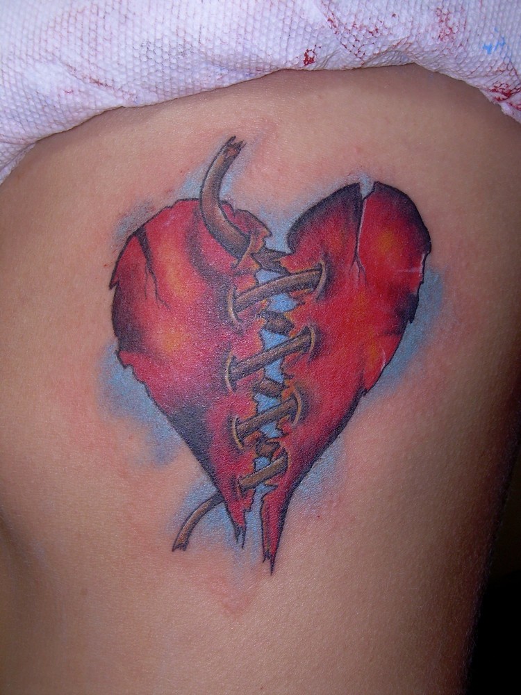 tatouage coeur brisé rattaché couleur sur fond bleu pastel