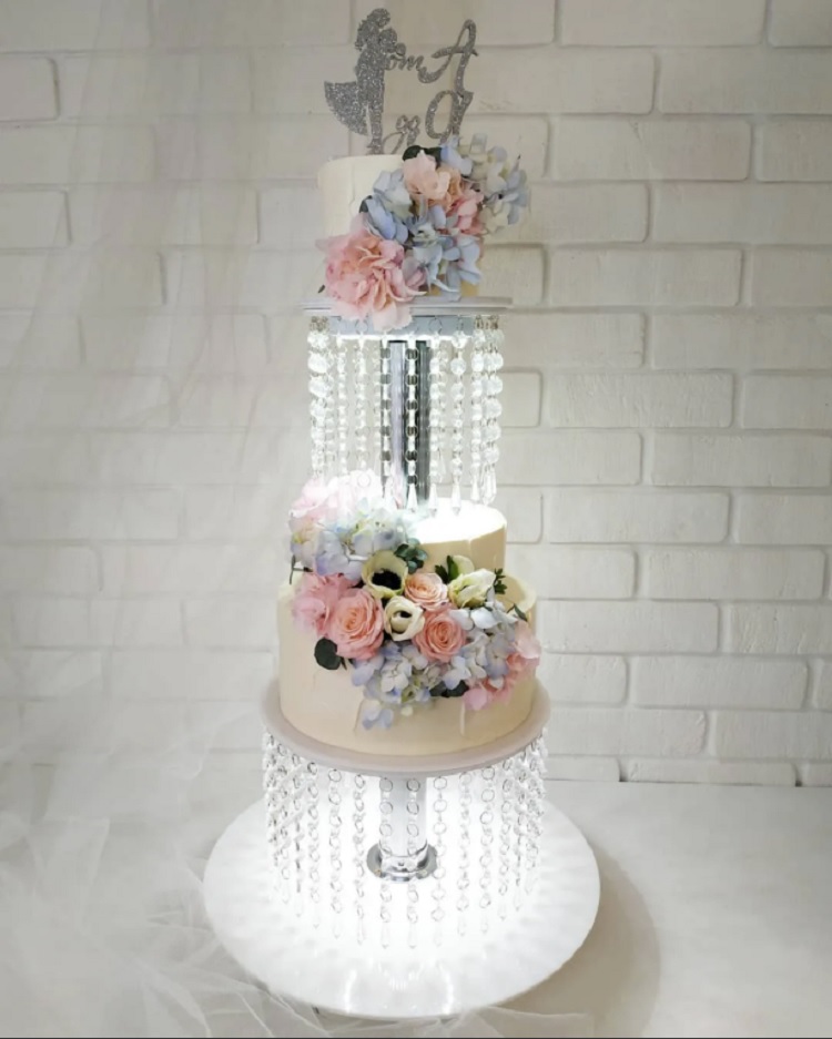 des gâteaux superposés décorée de fleurs, de guirlandes de cristaux et une lumière LED