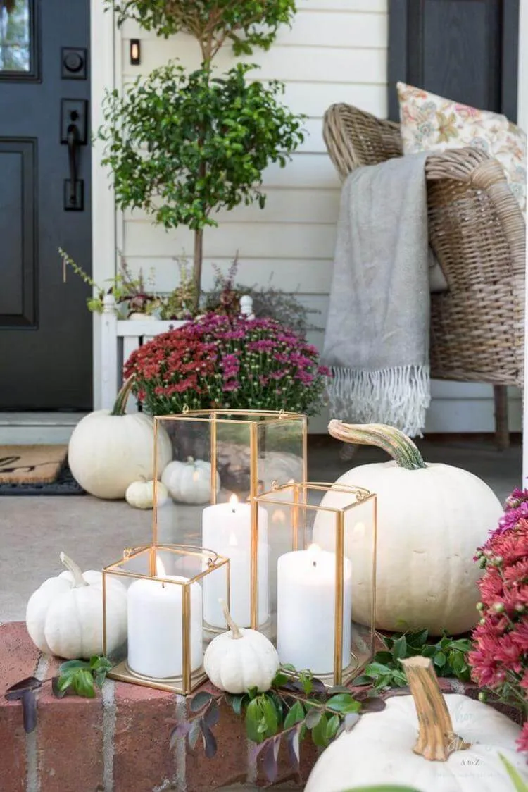 déco porche automne élégante avec lanternes en verre bougies et citrouilles blanches