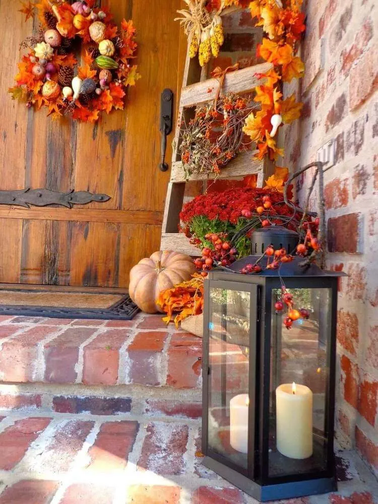 décoration automne extérieur lanterne en métal avec bougie citrouilles chrysanthèmes rouges couronne de porte feuilles automne