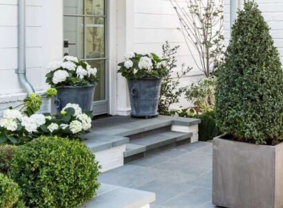 gros pot de fleurs extérieur en zinc et en ciment avec pétunias blancs et conifères