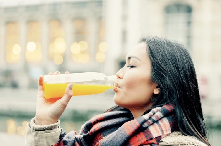 jeune femme boit jus orange frais pour booster ses défenses immunitaires