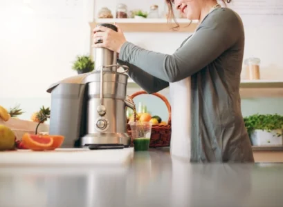 jeune femme faisant jus de fruits avec un extracteur de jus lent