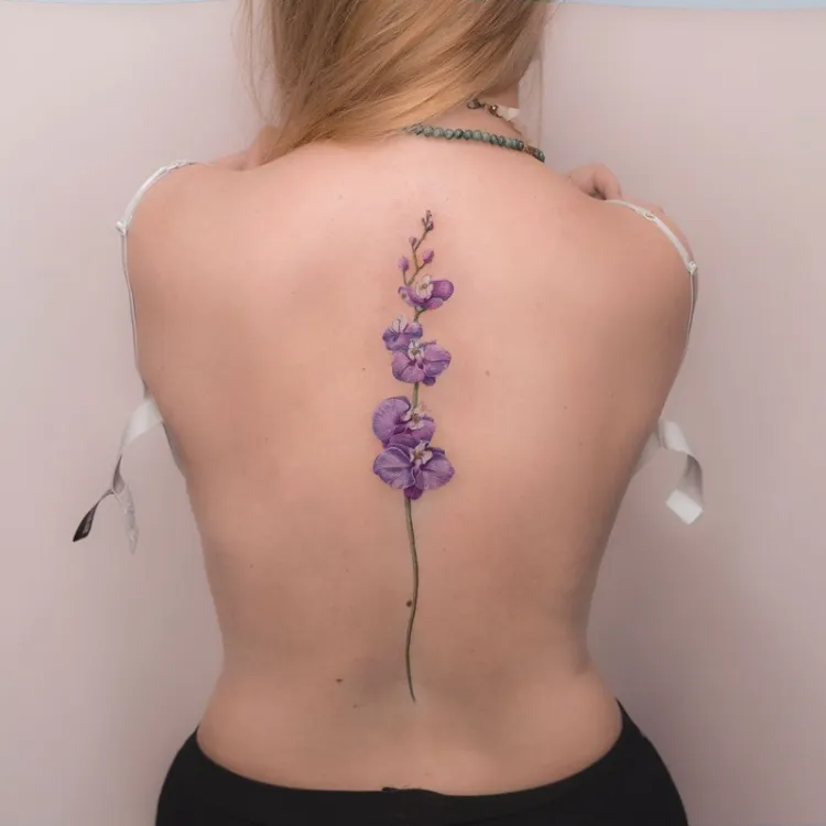 tatouage colonne vertebrale femme fleur violette inkage facile à cacher