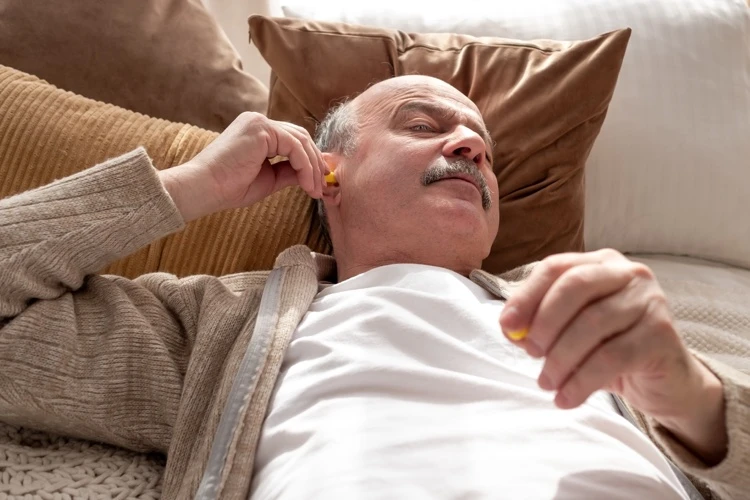 homme agé met des bouchons oreilles jaunes avant dormir