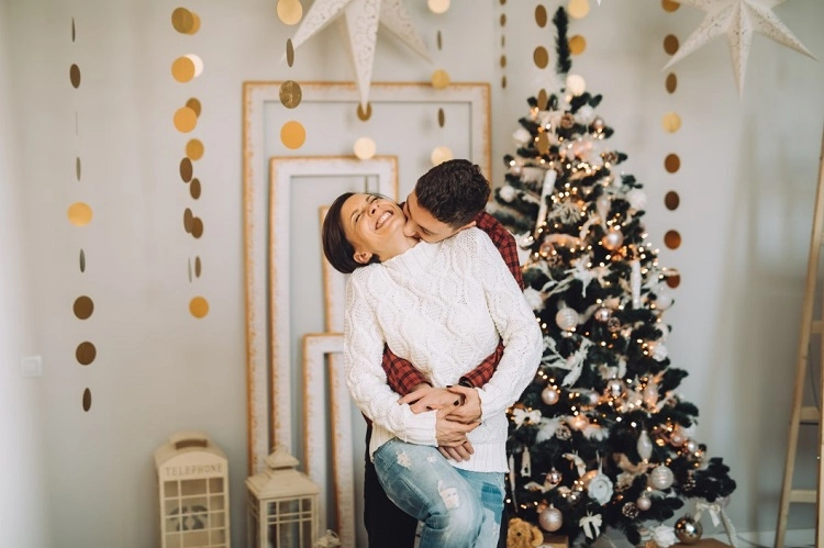 Couple s'embrasse Noël déco guirlandes sapin