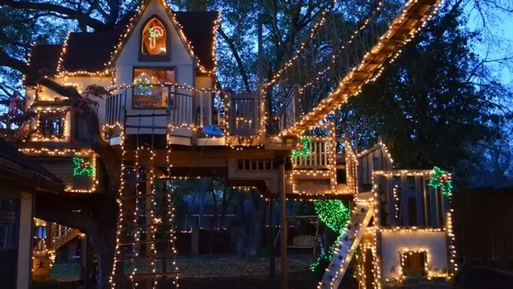 cabane enfant dans le jardin décorée pour Noel avec des guirlandes lumineuses