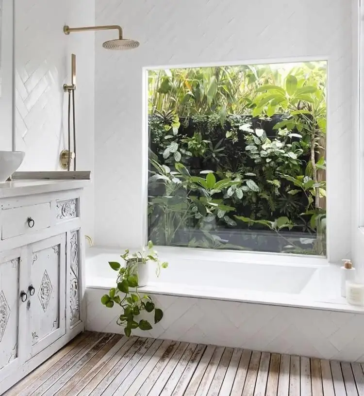 design biophilique dans la salle de bains carrelage métro blanc revetement de sol en bois fenetre donnant sur le jardin