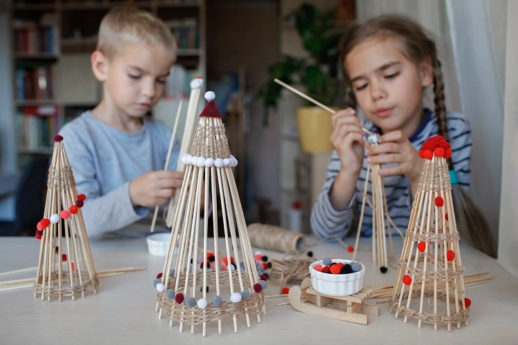 Deux enfants fabriquent un sapin de Noël en bois