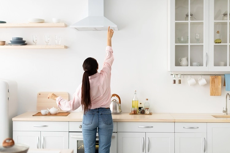 Femme utilise la hotte de la cuisine pour éliminer les odeurs et améliorer la qualité de l'air intérieur