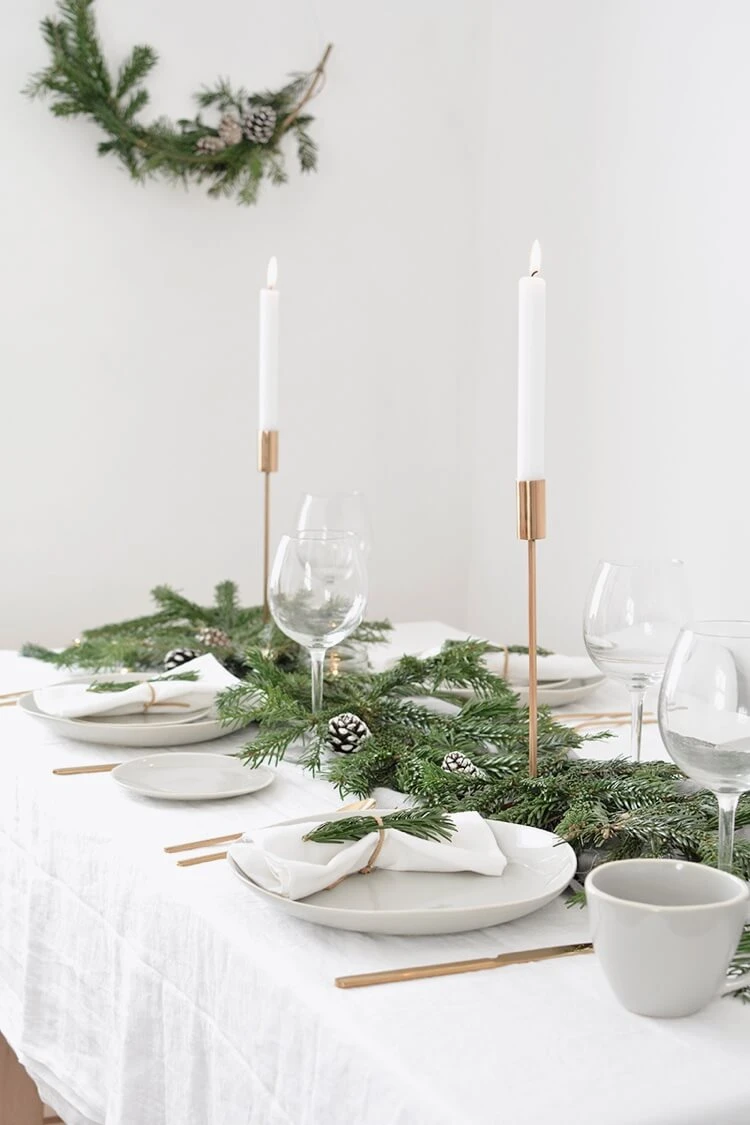 table de Noel minimaliste scandinave déco branches de sapin naturel et pommes de pin couverts de table cuivre