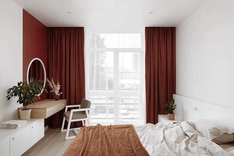 chambre à coucher lumineuse en blanc et bois avec déco rouge rideaux et pan de mur