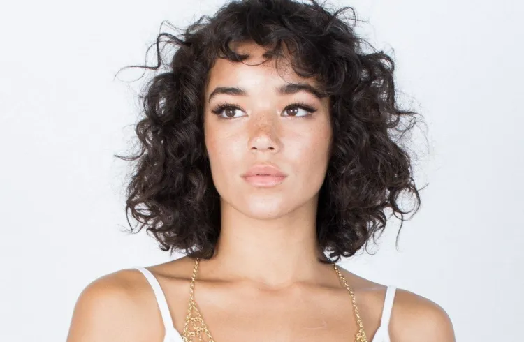 What hairstyle for a woman with baby bangs for curly hair of medium length works as a tweak