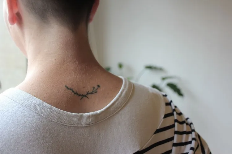 tattoo simple homme nuque branches et fleurs minimalistes