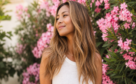 Femme aux cheveux blond caramel devant des fleurs roses en automne