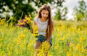 young girl collecting flowers on field