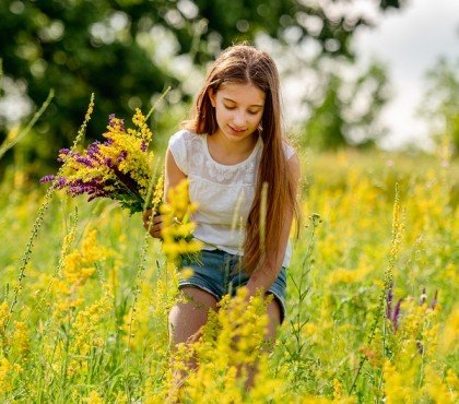 young girl collecting flowers on field
