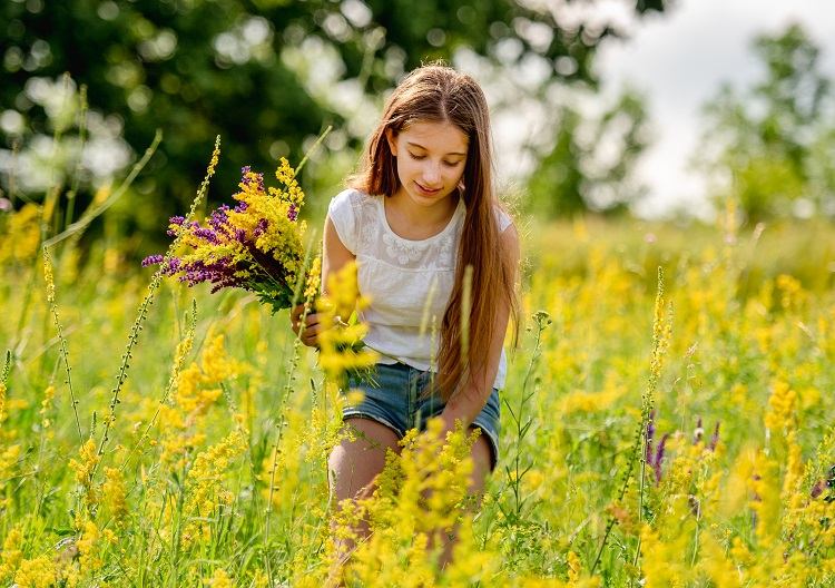 young girl collecting flowers on field