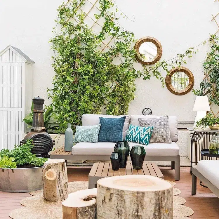 terrace boho chic avec plantes grimpantes et mur blanche décoré avec des mirroirs ronds