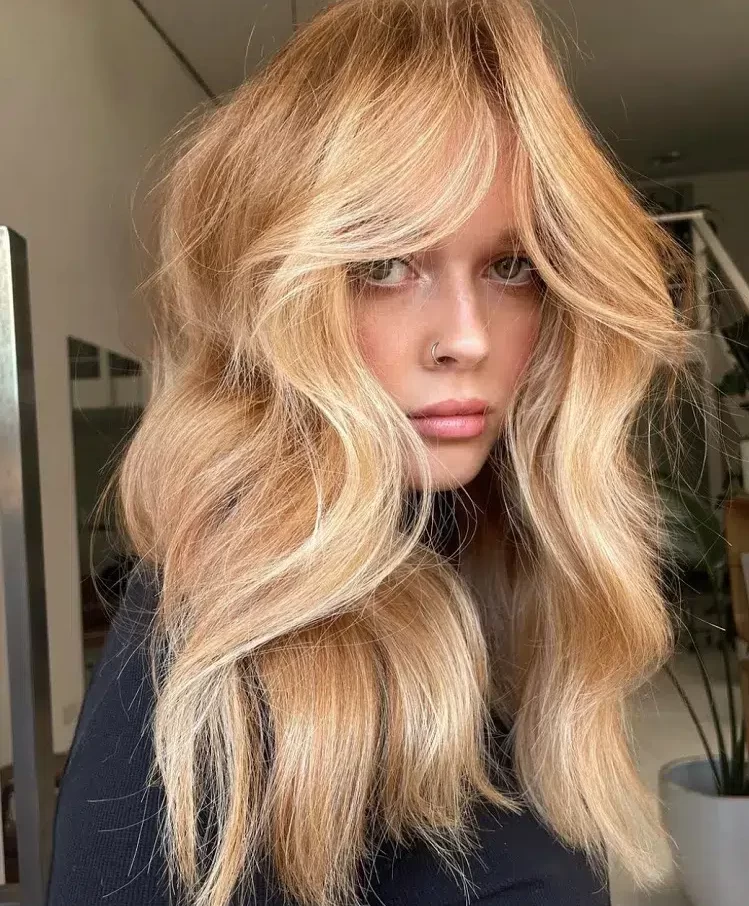 coupe bardot avec une frange longue chin bangs niveau menton cheveux longs wavy blonds femme tendance capillaire rentrée 2023