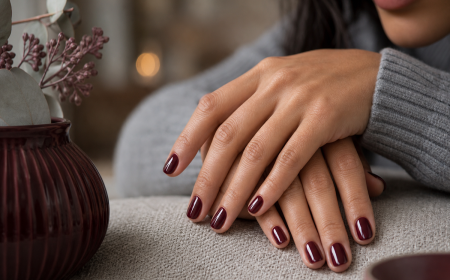 Manucure bordeaux tendance chic, ongles courts arrondis en vernis rouge bordeaux brillant, pull en laine gris-bleu