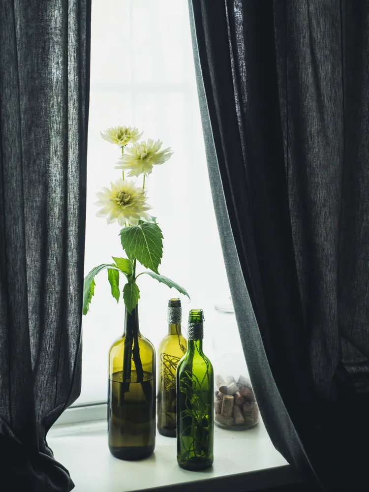 vase bouteille de vin avec des fleurs blanches sur le rebord de fenêtre