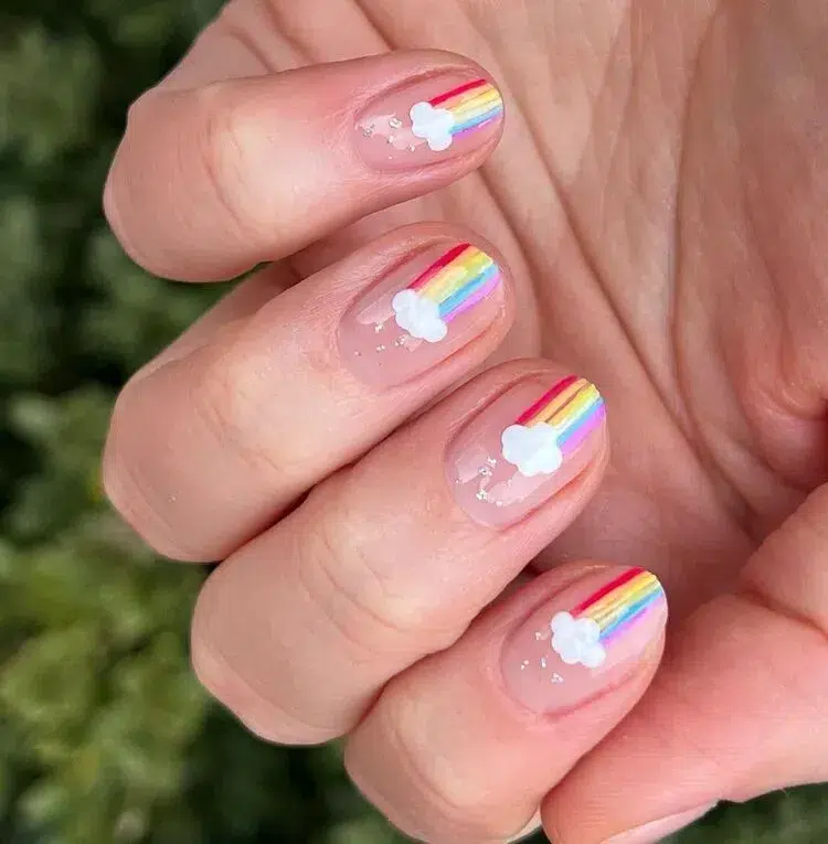 des nuages et de petits arcs en ciel sur des ongles très courts