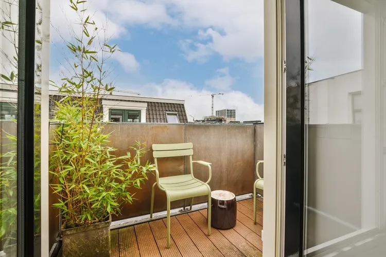 un balcon avec une chaise et une plante de bambou en pot